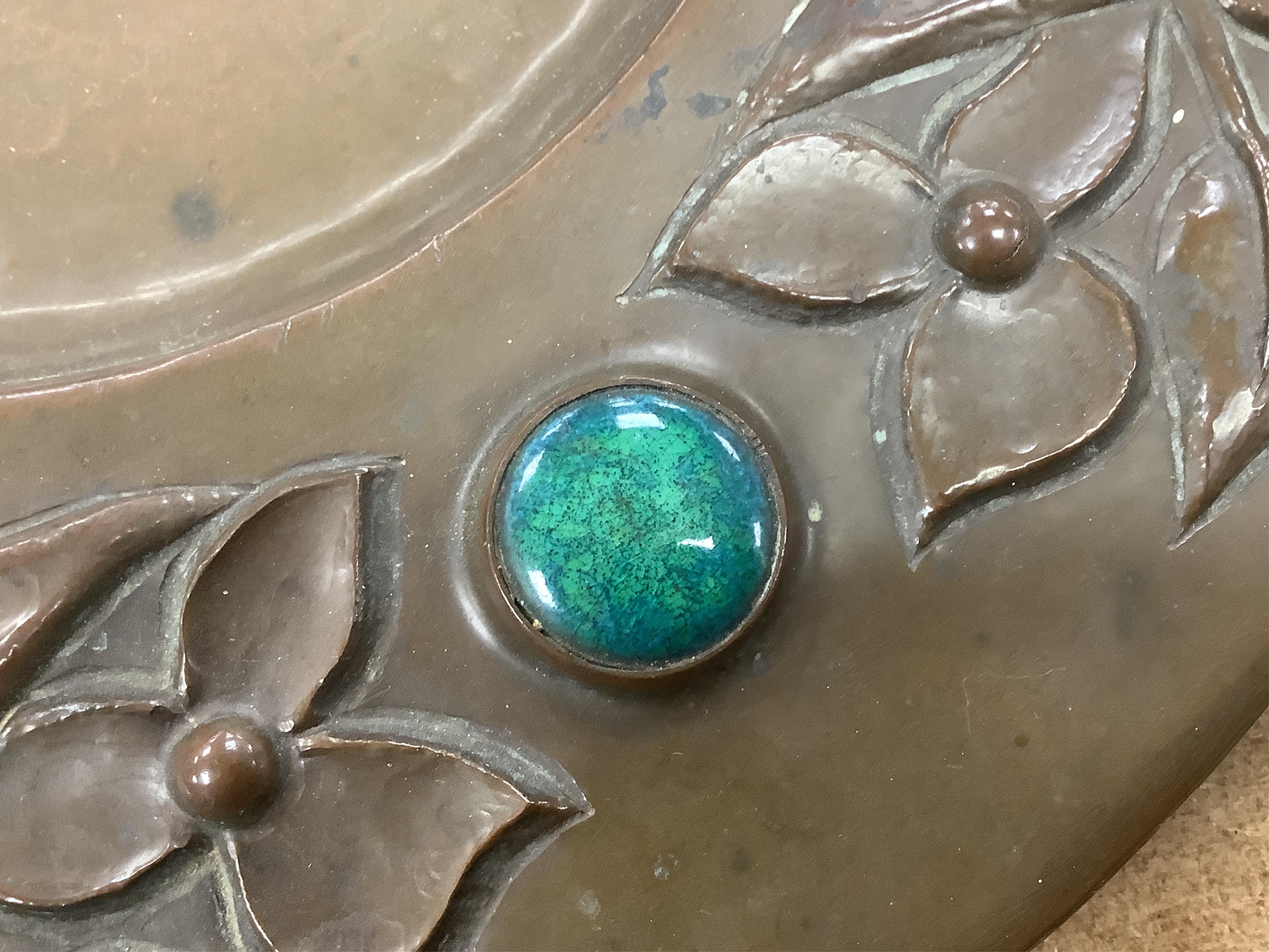 An Arts and Crafts embossed copper dish, in the manner of John Pearson, inlaid with Ruskin cabochons, unsigned, 32cm in diameter